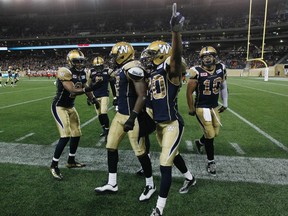 Winnipeg Blue Bombers' Matt Bucknor (2), Demond Washington (7) and Johnny Adams (20) celebrate Washington's interception late in the fourth quarter against the B.C. Lions in CFL action in Winnipeg Thursday, July 30, 2015.