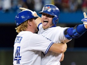Toronto Blue Jays third baseman Josh Donaldson, right reacts with first base coach Tim Leiper, left, after hitting a RBI single to defeat the Kansas City Royals during 11th inning AL baseball action in Toronto on Friday, July 31, 2015. (THE CANADIAN PRESS/Nathan Denette)