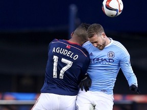 Juan Agudelo #17 of New England Revolution and Josh Williams #13 of New York City FC head the ball during the inaugural game of the New York City FC at Yankee Stadium on March 15, 2015 in the Bronx borough of New York City.The New York City FC defeated the New England Revolution 2-0.  Elsa/Getty Images/AFP