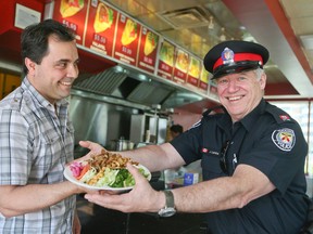 Chalak Ajchal, owner of Red and White, with Toronto Police Const. Jim Lambe ham it up for a photo inside the dining establishment that is frequented by 12 Division officers. (Veronica Henri/Toronto Sun)