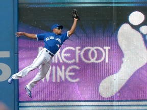 Toronto Blue Jays outfielder Ben Revere catches a fly ball off the bat of Kansas City Royals' Kendrys Morales against the outfield wall during the fourth inning of their MLB baseball game August 1, 2015 in Toronto. (JON BLACKER/The Canadian Press)