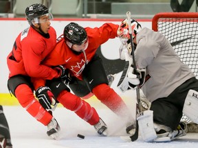 Joshua Ho-Sang (left) and Nick Merkley crash into goalie Mason McDonald during preparation on Sunday in Calgary for the 2016 world junior championship. (LYLE ASPINALL/POSTMEDIA NETWORK)