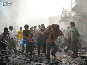 In this photo provided by the Syrian anti-government activist group Ariha Today, which has been authenticated based on its contents and other AP reporting, Syrian citizens help out an injured boy as another carries a man after a government forces warplane crashed in the centre of Ariha town in the northwestern province of Idlib, Syria, on Aug. 3, 2015. (Ariha Today via AP)