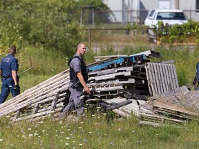 London Police officers search for evidence in a yard behind Sammy's Souvlaki on Trafalgar Street, where founder Sotirios (Sammy) Cardabikis and another unidentified man were injured in an early Sunday morning robbery. Craig Glover/The London Free Press/Postmedia Network