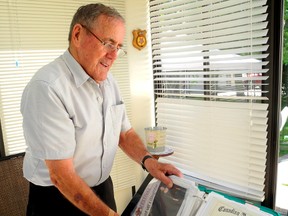 Gerald Austin, a 25-year Canadian Cold War naval veteran, leafs through a binder filled with records of his military service and a long-running benefits battle with Veterans Affairs at his home in Ailsa Craig, Ont., north of London. (Azzura Lalani. The London Free Press)