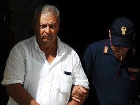 An Italian police officer takes in custody Michele Gucciardi, left, one of the 11 men suspected of helping No. 1 Cosa Nostra fugitive Matteo Messina Denaro, in Palermo, Italy, Monday, Aug. 3, 2015. (AP Photo/Alessandro Fucarini)