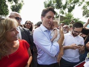 Liberal Leader Justin Trudeau hugs a baby while campaigning in Calgary on Monday. (REUTERS)