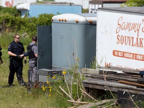 London Police officers search for evidence in a yard behind Sammy's Souvlaki on Trafalgar Street, where founder Sotirios (Sammy) Cardabikis and another unidentified man were injured in an early Sunday morning robbery, in London, Ont. on Monday August 3, 2015. Police are searching for multiple suspects. (CRAIG GLOVER, The London Free Press)