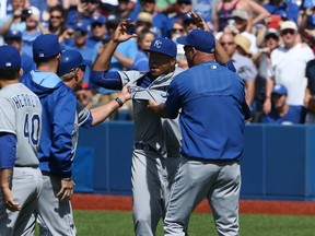 Royals’ Edinson Volquez is restrained by teammates against the Jays on Sunday. Volquez did the old “let me at ’em, let me at ’em” routine while being held back. (AFP)