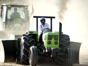 A heavy farm stock tractor leaves a cloud of dust behind it as it pulls a weight down the track at the Embro Truck and Tractor Pull on Friday, July 31, 2015. (BRUCE CHESSELL/Sentinel-Review)