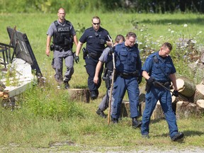 London Police officers search for evidence in a yard behind Sammy's Souvlaki on Trafalgar Street, where founder Sotirios (Sammy) Cardabikis and another unidentified man were injured in an early Sunday morning robbery, in London, Ont. on Monday August 3, 2015. Police are searching for multiple suspects. Craig Glover/The London Free Press/Postmedia Network