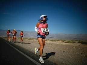 Shannon Farar-Griefer, 52, of Hidden Hills, California (R) runs away from her team after stopping to drink water as she competes in the Badwater Ultramarathon in Death Valley National Park, California in this July 15, 2013 file photo.      REUTERS/Lucy Nicholson/Files
