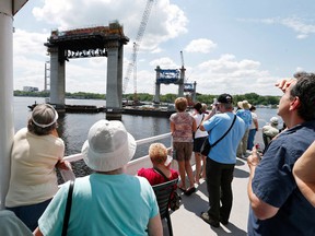 In this July 22, 2015 photo, people on the top deck of a river boat view piers toward the Minnesota side for the mile-long St. Croix Crossing bridge linking Minnesota and Wisconsin near Stillwater, Minn. Three times a month, 350 or more people head out on the 90-minute tours, with adults paying $10 apiece for the chance to view one of the biggest and most expensive bridge projects in Minnesota history. (AP Photo/Jim Mone)
