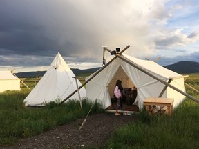 In this May 16, 2015, photo, Elly Melchor, 9, stands by a "glamping" tent in West Yellowstone, Mont. Glamping _ a term that combines glamour and camping _ offers the adventure of camping without roughing it. These accommodations, provided by Yellowstone Under Canvas, include beds and nearby bathroom facilities with hot water, fully functioning toilets and showers. (Jorge Melchor via AP)