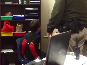 In this image made from video taken in August 2014, and provided by the American Civil Liberties Union on Tuesday, Aug. 4, 2015, an 8-year-old boy struggles and cries out as he sits in a chair with handcuffs around his biceps and his arms locked behind him while a school resource officer stands nearby, at an elementary school in Covington, Ky. The boy’s mother, along with the mother of a 9-year-old girl who was also handcuffed at the school, have filed a federal lawsuit against the school. The lawsuit says both children have attention deficit hyperactivity disorder, and school officials are aware of their disabilities. (American Civil Liberties Union via AP)