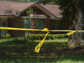 In this Monday, Aug. 3, 2015 photo, investigative tape is seen near a home in Pensacola, Fla. A triple homicide in Florida is being investigated as a possible ritualistic killing connected to the recent blue moon, Escambia County Sheriff David Morgan said Tuesday. (Tony Giberson/The Pensacola News Journal via AP)