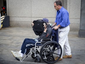 Irwin Lipkin, one of Bernard Madoff's longest-serving employees, covers his face as he is pushed in a wheelchair by his son Marc as they leave United States court in New York City following his sentencing hearing August 5, 2015. Lipkin was sentenced to six months in prison for falsifying records that helped the imprisoned fraudster Madoff carry out his multibillion-dollar Ponzi scheme. REUTERS/Mike Segar