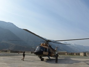 In this photograph taken on Feb. 24, 2014, an Afghan pilot walks near a military helicopter in Kunar province. Seventeen people were killed in a helicopter crash in the southern province of Zabul on Aug. 6, 2015, officials said. (AFP PHOTO/Shah Marai)