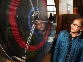 Cassidy Coutinho-Blankenau watches the colours form on the display as her dad Pete Blankenau cranks a generator at the TELUS Spark science centre in Calgary, Alberta, on November 13, 2011. MIKE DREW/Postmedia Network