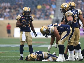 Bombers OL Jace Daniels (right) and RB Paris Cotton check on QB Drew Willy after he was sacked and injured against the Tiger-Cats during CFL action in Winnipeg on July 2, 2015. (Kevin King/Postmedia Network)