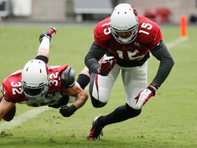 Arizona Cardinals' Tyrann Mathieu (32) tips the ball away from Cardinals' Michael Floyd (15) during an NFL football training camp practice, Monday, Aug. 3, 2015, in Glendale, Ariz. (AP Photo/Ross D. Franklin)