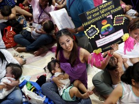 A mother displays a placard as she breastfeeds her child in Metro Manila on Aug. 1. A mass public breastfeeding was organized in several cities around the world in support of World Breastfeeding Week.