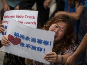 People whose relatives were aboard Malaysia Airlines flight MH370 kneel and cry in front of the media near the Malaysian embassy in Beijing after they scuffled briefly with police who stopped them from entering a road leading to the embassy August 7, 2015. Angry relatives of Chinese passengers aboard a Malaysia Airlines plane missing for more than a year clashed with police in Beijing on Friday as French officials extended the search for debris on remote Indian Ocean island beaches. The placard reads, "Mom is always here waiting for you, never will give up". REUTERS/Damir Sagolj