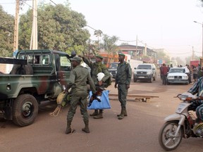 In this picture taken on March 7, 2015, soldiers gesture in front of La Terrasse restaurant where militants killed five people, including a French citizen and a Belgian citizen, in a gun attack in Bamako. One of the five people killed was a Belgian security officer with the European Union delegation in Mali, EU foreign policy chief Federica Mogherini said. (REUTERS/Adama Diarra)