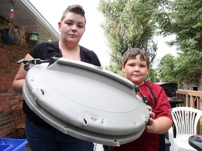 Michelle Lavoie and her 8-year-old son Tyler show off a lid that a bear pried off a garbage can at their New Sudbury home. Gino Donato/Sudbury Star