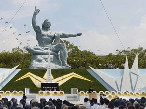 Doves fly over the Statue of Peace during a ceremony at Nagasaki Peace Park in Nagasaki, southern Japan Sunday, Aug. 9, 2015 to mark the 70th anniversary of the world's second atomic bomb attack.  The atomic bomb attack on this city that left more than 70,000 dead and hastened the end of World War II exactly 70 years ago. (Kyodo Photo via AP)