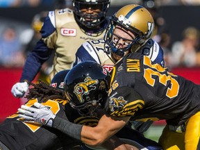 Winnipeg Blue Bombers' Rory Kohlert (C) is tackled by Hamilton Tiger-Cats' Mike Daly (front) and Courtney Stephen (L) during the first half of their CFL football game in Hamilton, August 9, 2015.    REUTERS/Mark Blinch