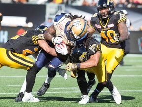 Winnipeg Blue Bombers' Troy Stoudermire, centre, is tackled by Hamilton Tiger-Cats' Rico Murray, right, and teammate Emanuel Davis, left, during the first-half of CFL football action in Hamilton, Ont., on Sunday, August 9, 2015. THE CANADIAN PRESS/Peter Power