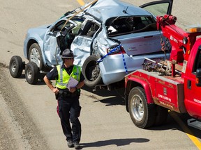 Edmonton Police Service officers respond to a crash involving a Dodge Avenger and a semi truck on the westbound portion of Anthony Henday Drive past 91 Street in Edmonton, Alta., on Monday August 10, 2015. The highway was closed for hours as police investigated and tow truck drivers cleaned up the debris. Ian Kucerak/Edmonton Sun/Postmedia Network