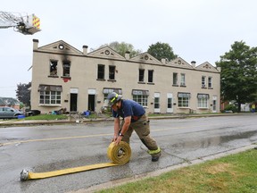 Owen Sound firefighter Jay Forslund rolls up hose Monday after he and members of three fire departments battled several blazes in the city early Monday morning. The 10 plex, background, is among seven fire scenes being investigated by police and the Ontario office of the Fire Marsha. Fifteen families were left homeless. (James Masters/Owen Sound Sun Times/Postmedia Network)