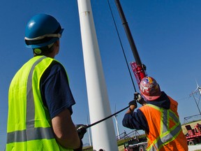 Alex Baird (left) and Ron Murphy (right) work the tag lines while a crane operator lifts a wind turbine roof back up the tower after a generator exchange. John Stoesser photos/Pincher Creek Echo.