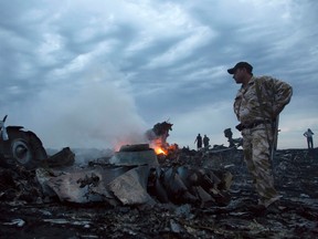 In this July 17, 2014 file photo people walk amongst the debris, at the crash site of a passenger plane near the village of Grabovo, Ukraine. Dutch prosecutors have said in a statement on Tuesday, Aug. 11, 2015 for the first time that they have found possible parts of a BUK missile system at the site in eastern Ukraine where Malaysia Airlines Flight 17 was brought down last year, killing all 298 people on board. Prosecutors say the parts "are of particular interest to the criminal investigation as they can possibly provide more information about who was involved in the crash of MH17." (AP Photo/Dmitry Lovetsky, File)