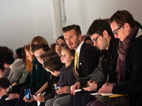 David Beckham carries his daughter Harper as he sits next to his sons Brooklyn, Romeo and Cruz, before the Victoria Beckham Fall 2014 collection during New York Fashion Week February 9, 2014. REUTERS/Eric Thayer