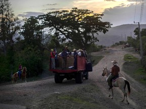 In this July 26, 2015 photo, horsemen take their horses back to a farm after a rodeo show in Santiago, Cuba. The city sits 800 kilometers east from Havana on highways that narrow outside the capital to roads of horsecarts, bicyclists and stray cows. (AP Photo/Ramon Espinosa)