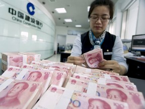 A clerk counts Chinese 100 yuan banknotes at a branch of China Construction Bank in Hai'an, Jiangsu province in this June 10, 2014 file photo. (REUTERS/China Daily/Files)