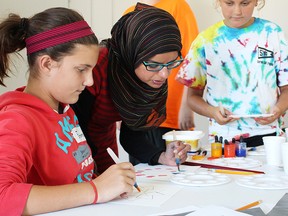 Artist Aruba Mahmud offers some tips to kids in a summer camp program at Gallery in the Grove as they make geometric patterns with watercolour paint. Mahmud is one of three artists helping lead the second annual Visiting Artist in Lambton Schools (VALS) in the Park camp. (Tyler Kula/Sarnia Observer/Postmedia Network)