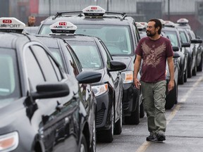 A long line of airport taxi drivers rally before protesting a new contract between the airport and Coventry Connections that would require drivers to pay $5.00 per trip for fares from the airport. Tuesday August 11, 2015. Errol McGihon/Ottawa Sun/Postmedia Network