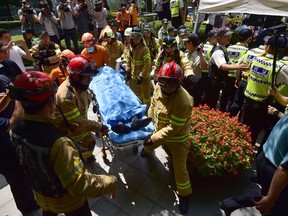 South Korean fire fighters take away a man (C, on stretcher) who set himself on fire outside the Japanese embassy in Seoul on August 12, 2015 during a protest to demand Tokyo's apology for forcing women into military brothels during World War II. Witnesses said other protesters and emergency responders moved quickly to douse the flames and the man was taken from the scene by stretcher. AFP PHOTO / JUNG YEON-JE