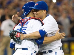 Toronto Blue Jays catcher Russell Martin congratulates pitcher Roberto Osuna on the save at the end of the ninth inning of their AL baseball game against the Oakland Athletics in Toronto on Tuesday August 11, 2015. The Blue Jays defeated the Athletics 4-2. THE CANADIAN PRESS/Fred Thornhill