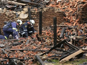 Investigators from office of the Ontario Fire Marshal dig on their hands an knees in the rumble behind the foundation of a home on 15th St. E gutted by fire on Monday August 10, 2015 in Owen Sound, Ont.  Seven suspicious fires are being investigated that left 15 families homeless Monday.  James Masters/Postmedia Network