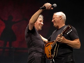 Pink Floyd musicians Roger Waters (L) and David Gilmour, prepare to embrace on stage during a concert at the O2 arena, in London May 12, 2011. REUTERS/Sean Evans/Handout