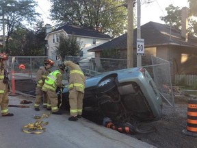 Fire crews work to stabilize a vehicle which landed on a gas line in a construction pit after crashing along Main St. near Riverdale Ave. Thursday morning. (OTTAWA FIRE SERVICE submitted image)