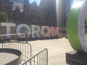 The 3D Toronto sign being moved in Nathan Phillips Square caught a lot of attention on Thursday, Aug. 13, 2015, but didn't stop people from posing for pictures. The sign was moved for the Parapan Am Games closing ceremonies but city officials stressed it will be moved back to the spot by the reflecting pond. (DON PEAT/Toronto Sun)