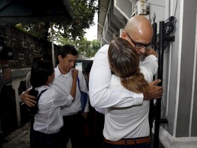 Canadian teacher Neil Bantleman (R) and Indonesian teaching assistant Ferdinand Tjiong (2nd L) hug their wives, as they arrive at a South Jakarta court April 2, 2015. Bantleman and Tijong saw their convictions for sexually abusing kindergarten boys at a prestigious international Jakarta school overturned on Friday, Aug. 14. The controversial verdict against Bantleman and Tijong came after a four-month trial that critics say was fraught with irregularities, raising foreign investors' concerns about legal certainty in Southeast Asia's biggest economy. REUTERS/Darren Whiteside