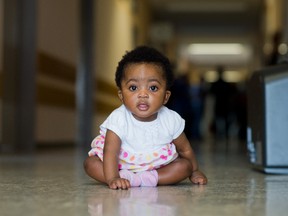 Six-month-old Angela Merkel Ade sits in a corridor in the Oststadtkrankenhaus refugee accommodation in Hanover, Germany, in this Aug. 13, 2015 photo. Her mother Ophelya Ade, a refugee from Ghana, named her daughter after the German chancellor. (Julian Stratenschulte/dpa via AP)
