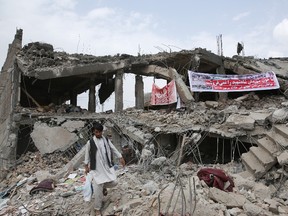 An Afghan man walks through the debris of a market destroyed by the blast of last Friday's truck bomb in Kabul, Afghanistan, Thursday, Aug. 13, 2015. The Afghan government on Thursday sent a high-level delegation to Pakistan to discuss an action plan after Islamabad-hosted peace talks with the Taliban were suspended last month, officials said. Arabic on banner reads: We will not sell out our Shah Shahid's martyrs' blood. We want to know all secrets of this mysterious attack. (AP Photo/Massoud Hossaini)